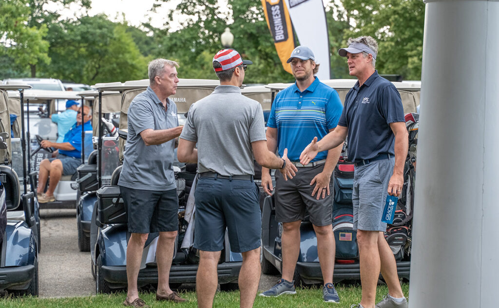 a group of men shaking hands standing next to golf carts
