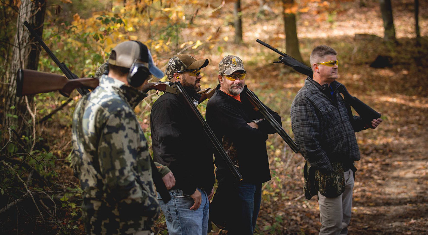 four men in the woods holding guns