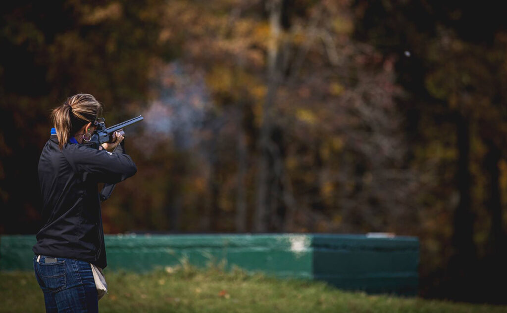 a woman shooting a gun in the woods